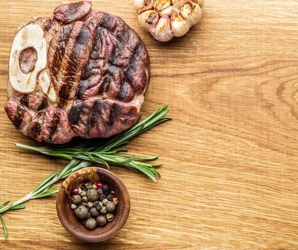 Rundvlees steaks met kruiden op een houten dienblad. — Stockfoto