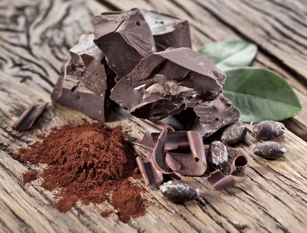 Chocolate and cocoa bean over wooden table. — Stock Photo, Image