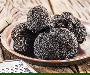 Eski ahşap masa üzerinde plaka üzerinde siyah truffles.
