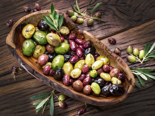 Aceitunas de mesa enteras en el cuenco de madera de la mesa . — Foto de Stock