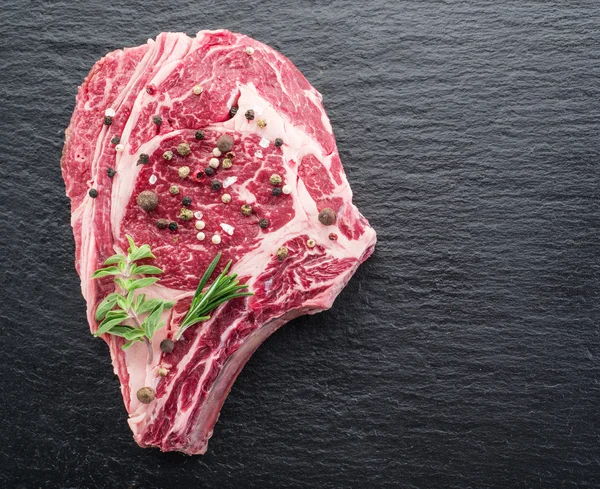 Rib eye steak with spices on the black background. — Stock Photo, Image