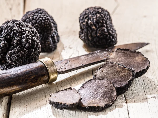 Trufas pretas na velha mesa de madeira. — Fotografia de Stock