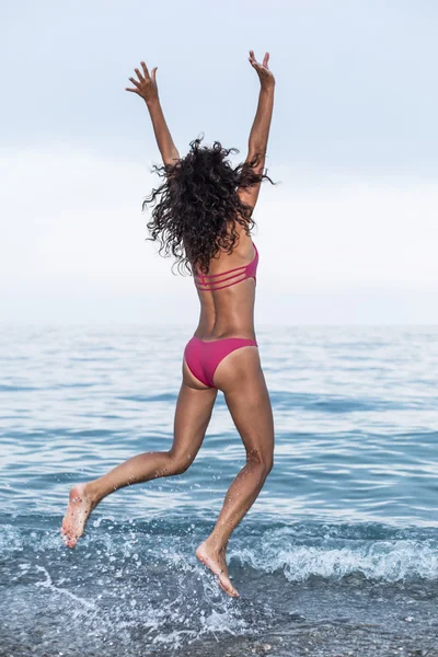 Mujer feliz saltando en la playa del mar . — Foto de Stock