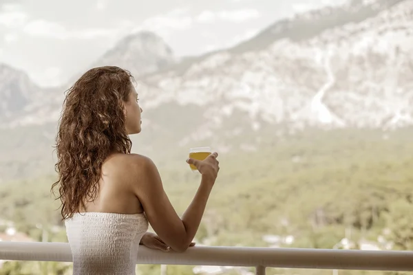 女人在酒店的阳台上喝橙汁. — 图库照片