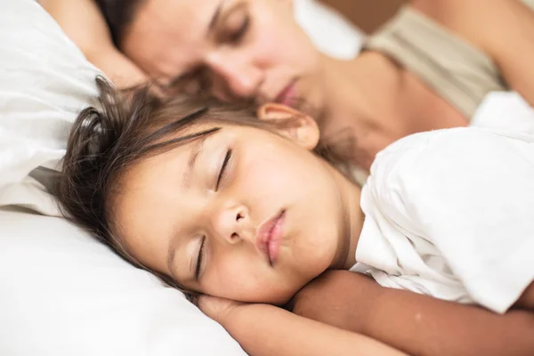 Sovande kid flicka och hennes mamma i sängen. — Stockfoto