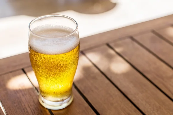 Verre de bière légère sur la table en bois . — Photo