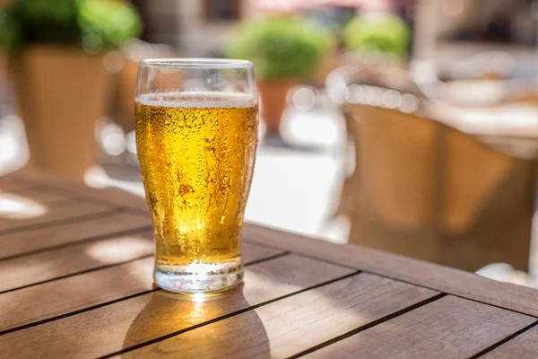Ποτήρι ελαφριά μπύρα στο ξύλινο τραπέζι. — Φωτογραφία Αρχείου