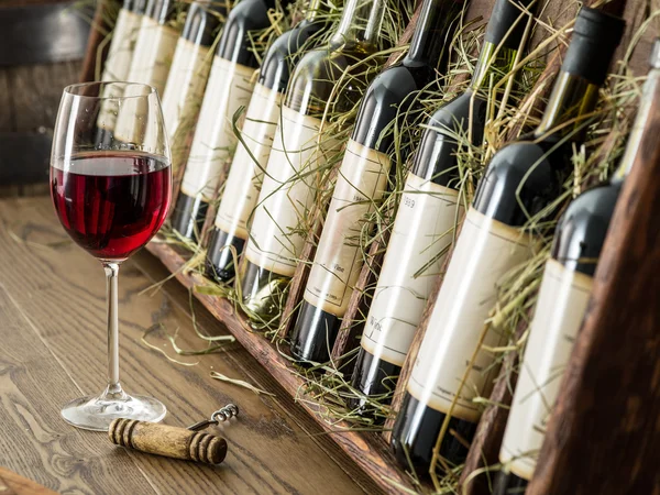 Glas rött vin och flaskor i bakgrunden. — Stockfoto