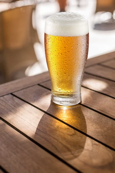 Vaso de cerveza ligera en la mesa de madera . — Foto de Stock
