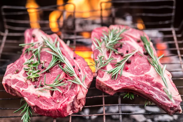 Filetes de costilla y parrilla con fuego ardiente detrás de ellos . — Foto de Stock