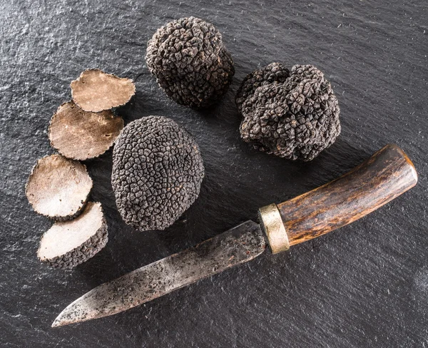 Black truffles and truffle slices on the graphite board. — Stock Photo, Image