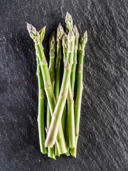 Germogli di asparagi sullo sfondo nero . — Foto Stock