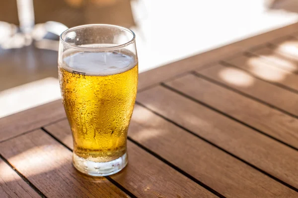 Стакан светлого пива на деревянном столе . — стоковое фото