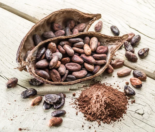 Cocao em pó e feijão cocao na mesa de madeira . — Fotografia de Stock