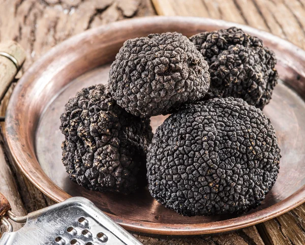 Black truffles on the plate on the old wooden table. — Stock Photo, Image