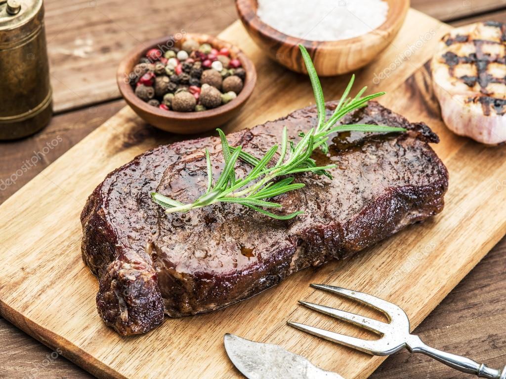 Steak Ribeye with spices on the wooden tray. Stock Photo by ©Valentyn