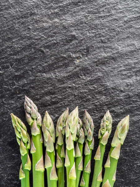 Germogli di asparagi sullo sfondo nero . — Foto Stock