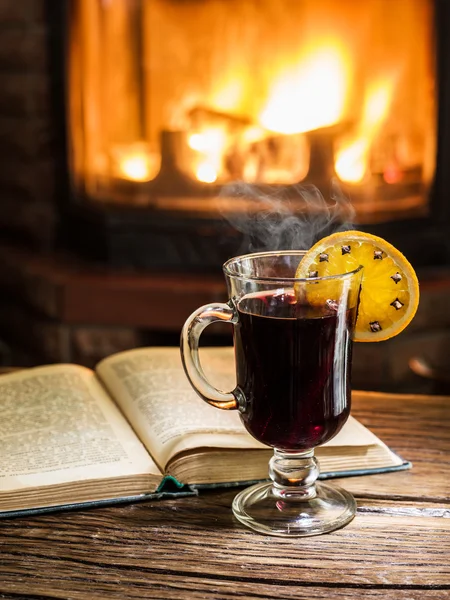 Vino caliente caliente con especias y un libro sobre la mesa de madera . — Foto de Stock