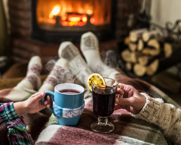 Aquecimento e relaxamento perto da lareira com uma xícara de bebida quente . — Fotografia de Stock