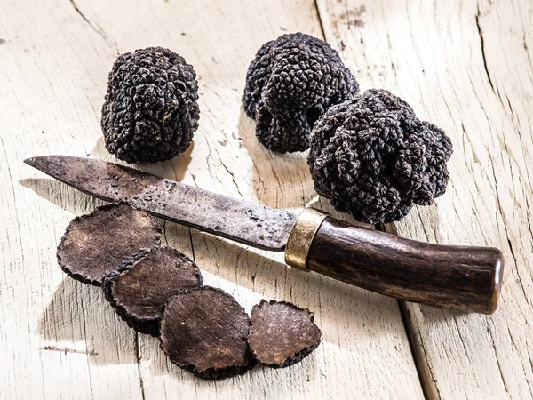 Trufas pretas na velha mesa de madeira. — Fotografia de Stock