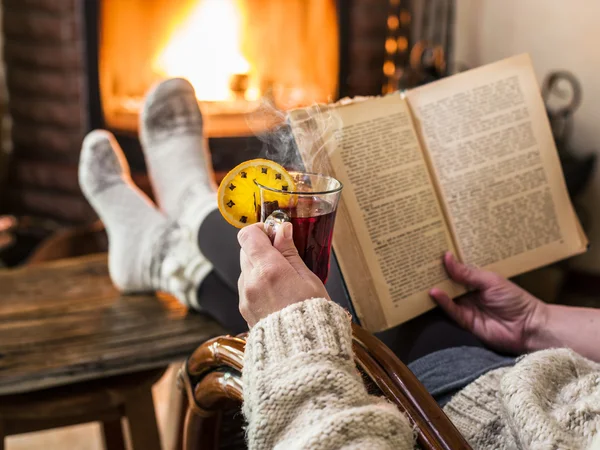 Hot mulled wine and book in woman hands. Relaxing in front of bu — Stock Photo, Image