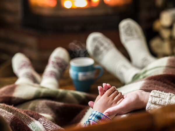 Warming and relaxing near fireplace. Mother and daughter holding