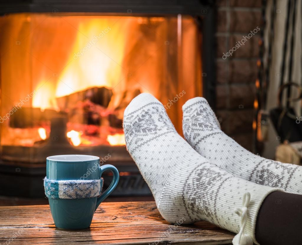 Warming and relaxing near fireplace with a cup of hot drink. — Stock