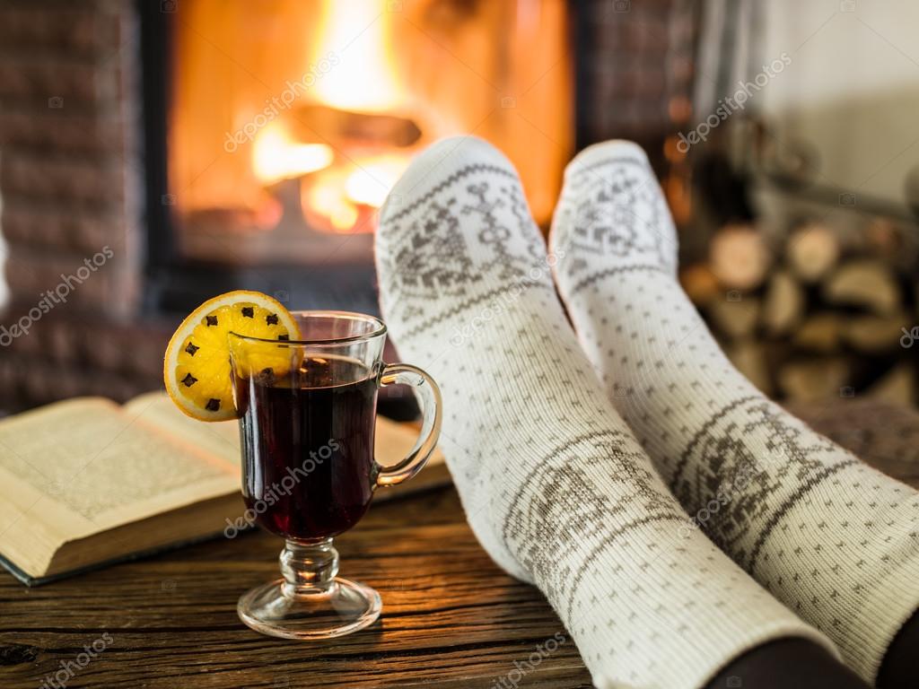 Warming and relaxing near fireplace with a cup of hot wine and a