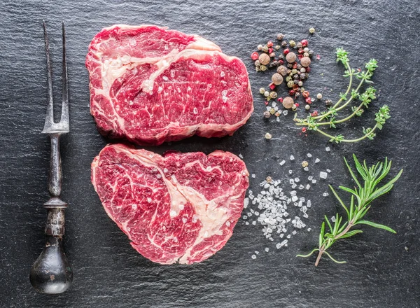 Rib eye steak, a fűszerek, a fekete háttér. — Stock Fotó