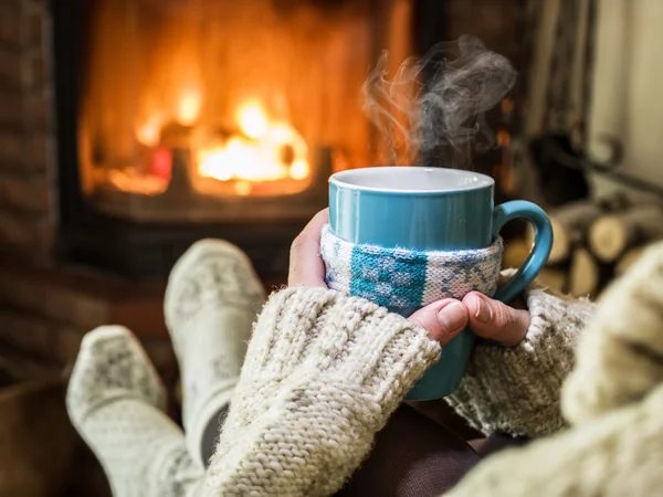 Opwarming van de aarde en ontspannen bij de open haard met een kopje warme drank. — Stockfoto