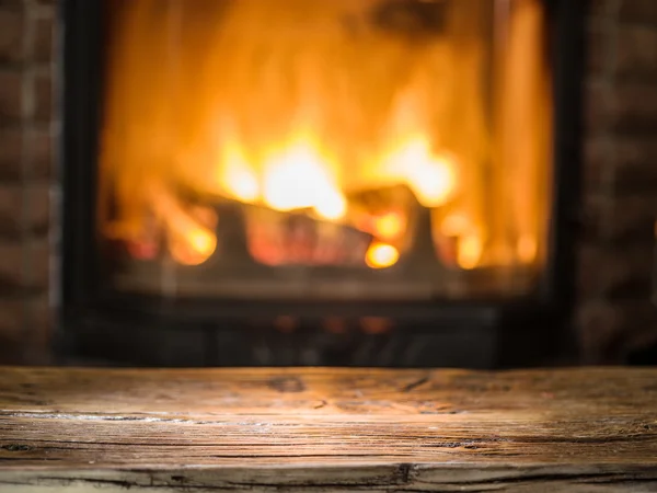 Antigua mesa de madera y chimenea con fuego caliente en el fondo . —  Fotos de Stock