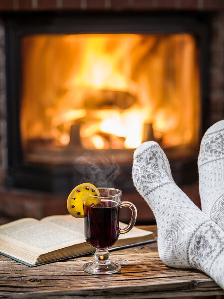 Warming and relaxing near fireplace with a cup of hot wine.