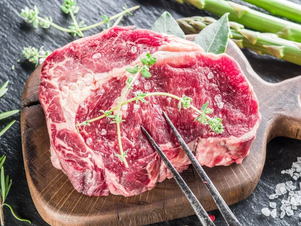 Rib eye steak met specerijen op de zwarte achtergrond. — Stockfoto
