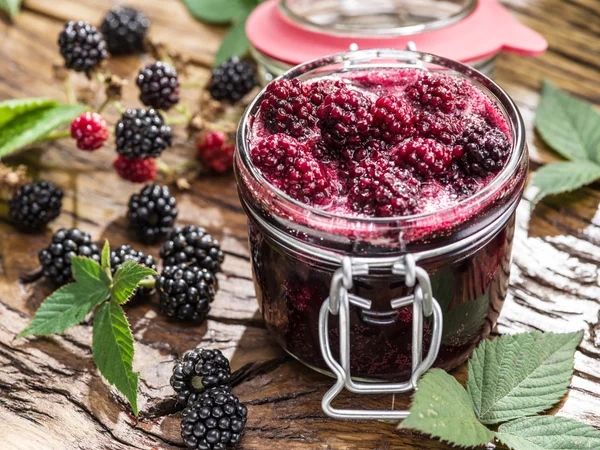 Blackberry confiture on old wooden table. Several fresh berries are near it. — Stock Photo, Image