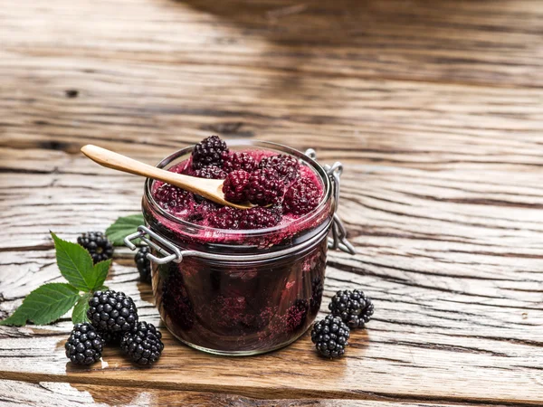 Brombeerkonfitüre auf altem Holztisch. mehrere frische Beeren sind in der Nähe. — Stockfoto