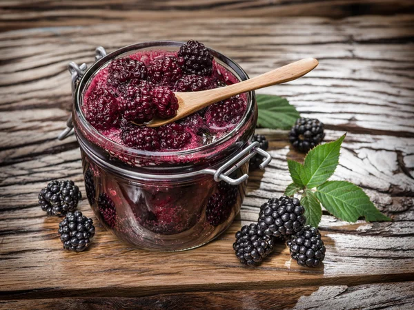 Brombeerkonfitüre auf altem Holztisch. mehrere frische Beeren sind in der Nähe. — Stockfoto