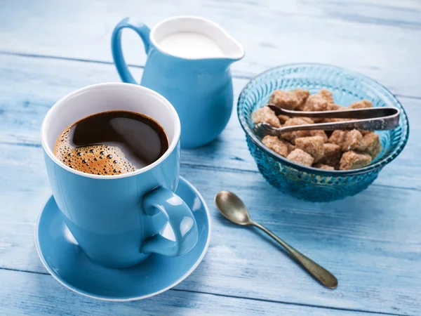 Ceașcă de cafea, ulcior de lapte și cuburi de zahăr din trestie . — Fotografie, imagine de stoc