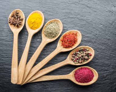 Ahşap kaşıklardaki renkli baharatların çeşitli çeşitleri.
