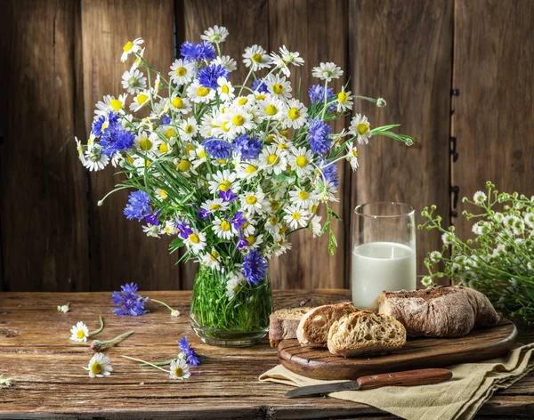 Bukett av fältet blommor, glas mjölk och mjukt bröd på världe — Stockfoto