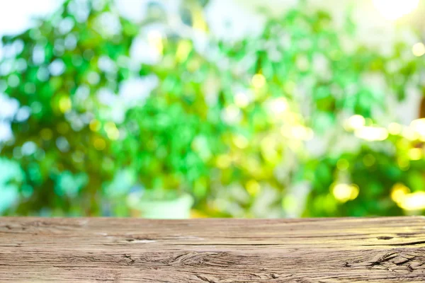 Escritorio de madera y follaje borroso en el fondo . —  Fotos de Stock