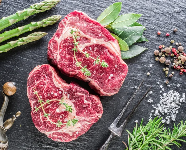 Rib eye steak with spices on the black background. — Stock Photo, Image