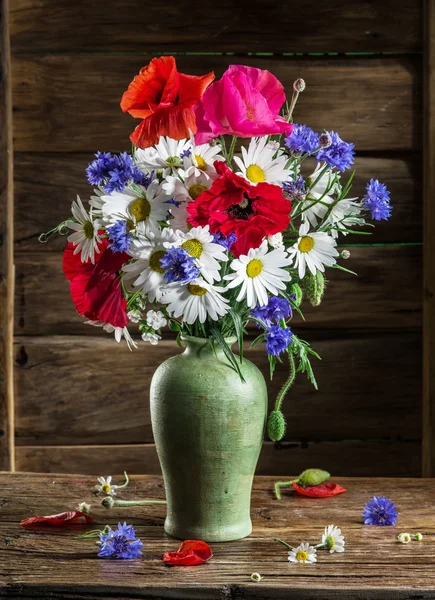 Buquê de flores de campo no vaso na mesa de madeira . — Fotografia de Stock