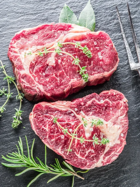 Rib Eye Steaks mit Gewürzen auf schwarzem Hintergrund. — Stockfoto