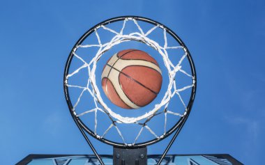 Net düşen basketbol. Arka planda mavi gökyüzü.