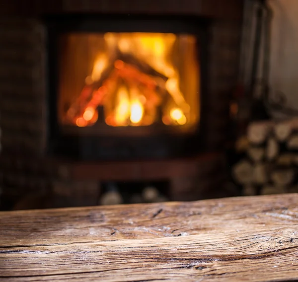 Antigua mesa de madera y chimenea con fuego caliente en el fondo . —  Fotos de Stock