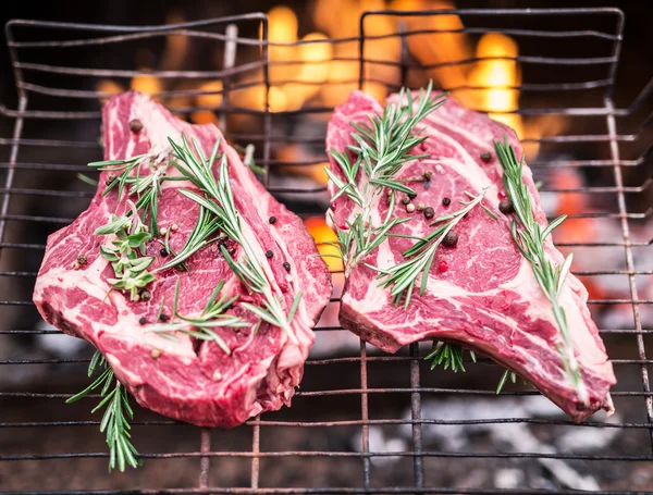 Filetes de costilla y parrilla con fuego ardiente detrás de ellos . — Foto de Stock