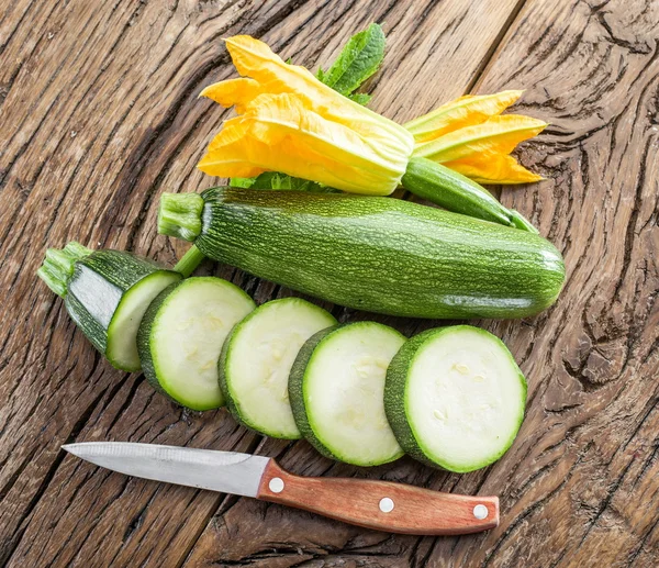 Calabacín con rodajas y flores de calabacín en una mesa de madera . —  Fotos de Stock