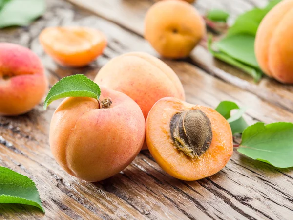 Apricots and its cross-section on the old wooden table. — Stock Photo, Image