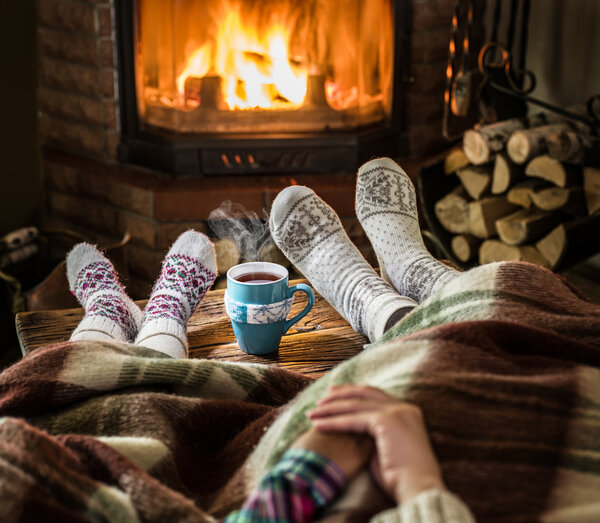 Warming and relaxing near fireplace. Mother and daughter holding