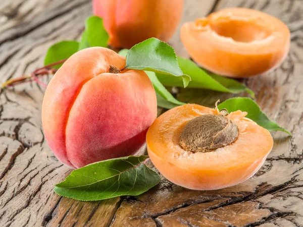 Apricots and its cross-section on the old wooden table. — Stock Photo, Image